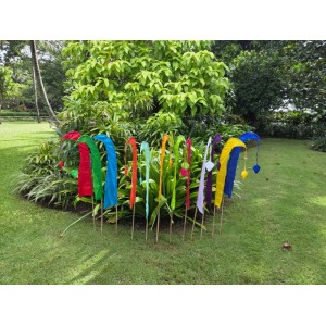 Bunte Balifahnen Umbul-Umbul mit geschwungenen Bambusstielen als exotische Gartendekoration auf einer Wiese.