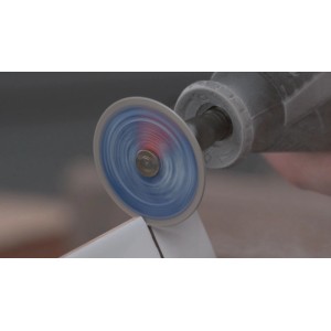 Disque diamant Dremel Max EZ SpeedClic SC545DM en rotation coupant précisément un carreau de céramique blanc.