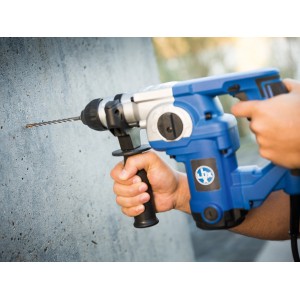 Punta per martello perforatore LUX Comfort SDS-Plus che fora un muro di cemento con un martello perforatore blu.