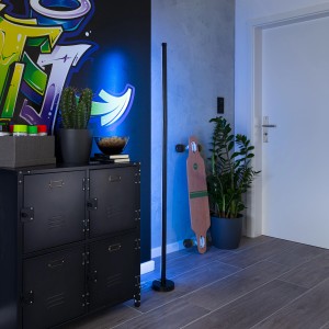 Lampada da terra LED Näve Digital Motion Light nera, 150 cm, con effetti luce RGB in un soggiorno moderno.