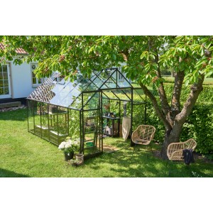 Serre noire Halls Qube+ 812 (9,9 m²) dans jardin avec plantes et mobilier de jardin.