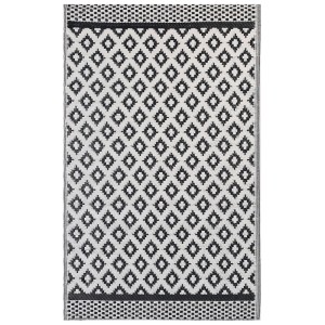 Beliani Outdoor-Teppich Thane, 120x180 cm, mit geometrischem Muster in Schwarz und Weiß.