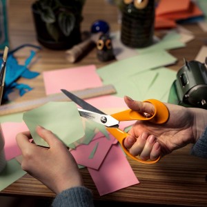 Mani che tagliano carta con le forbici universali Fiskars Classic S90 (21 cm) su una scrivania.
