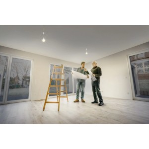 Deux artisans avec plan sous les lampes de rénovation Osram dans la pièce. Lampes de travail pour le chantier.