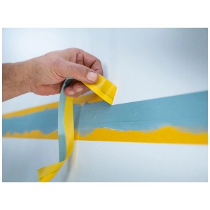 Application du ruban adhésif washi doré LUX sur un mur pour des bords de peinture précis.