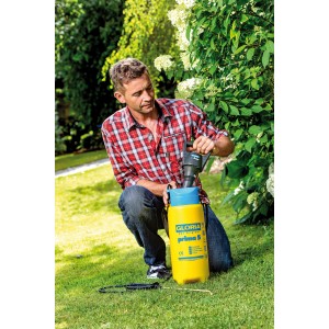 Homme utilisant le pulvérisateur à pression Gloria AutoPump Set pour l'entretien des plantes dans le jardin.