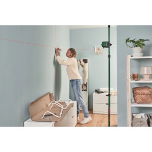 Donna utilizza il laser a linee incrociate Bosch UniversalLevel 2 per l'allineamento sulla parete.