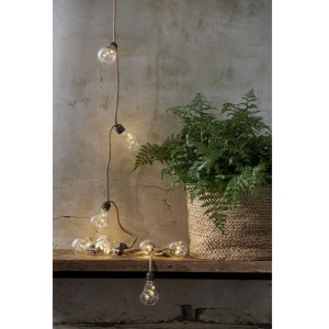 Catena luminosa Jutta LED con 10 lampadine chiare e cavo in juta su mensola, luce calda per arredo accogliente.