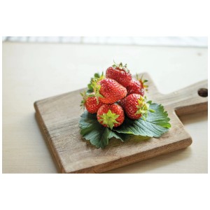 Fragole fresche Thuriga su tagliere di legno. Frutti rossi e succosi con foglie verdi.
