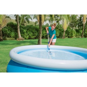 Femme nettoyant piscine avec aspirateur électrique Aquascan. L'aspirateur a une poignée télescopique.