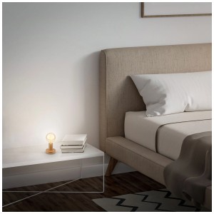 Lampe de table Briloner E27 aspect bois sur table de chevet à côté du lit.
