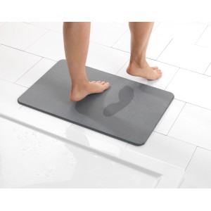 Tappetino da bagno grigio Wenko Simi 60x39 cm con impronte su piastrelle bianche.
