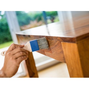 Mano che olia tavolo in legno con pennello per cera LUX 50mm. Pennello con testa blu e manico in legno chiaro.