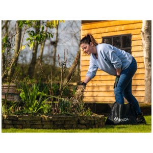 Femme remplissant le sac de collecte Bosch (28l/50kg) pour UniversalShredder avec des déchets de jardin.