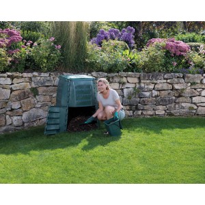 Composteur Garantia Thermostar 1000 l vert avec femme retirant du compost dans le jardin.