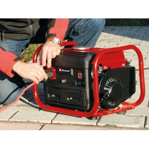 Groupe électrogène Einhell TC-PG 10 E5 : Générateur portable avec cadre rouge et personne branchant un câble.