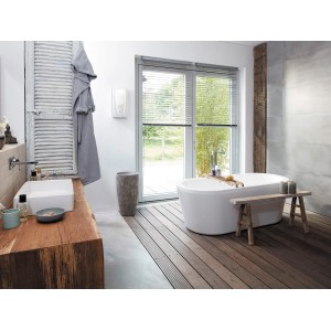 Chauffe-eau instantané Clage DCX Next L dans salle de bain moderne avec baignoire et éléments en bois.