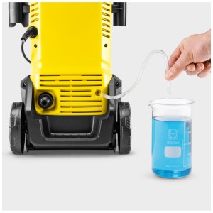 Nettoyeur haute pression Kärcher K 3 Home jaune avec tuyau d'aspiration dans un bécher avec liquide de nettoyage.