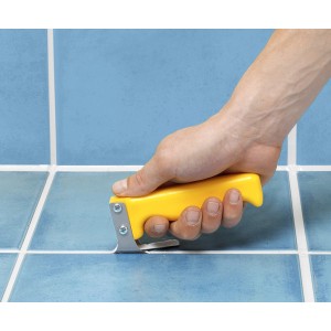 Leva stucco con manico giallo in uso per rimuovere lo stucco su piastrelle blu.