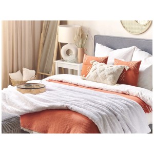 Morbida coperta bianca Beliani Bjas (200x220 cm) su un letto con cuscini e decorazioni.