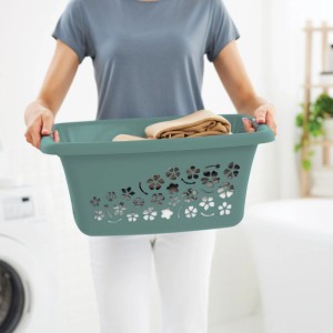 Personne porte panier à linge Rotho Flowers 25l vert avec décor floral et linge dans une buanderie.