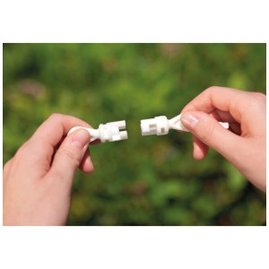 Gros plan : Deux mains connectent un connecteur blanc sur fond vert.