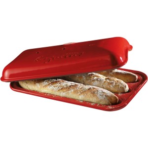 Moule à baguette en céramique rouge Emile Henry avec trois baguettes sous le couvercle.