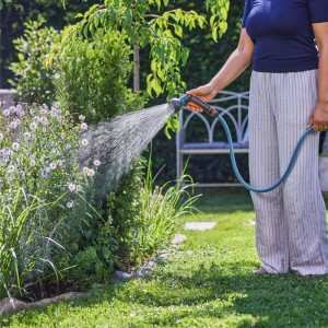 Donna che innaffia il giardino con la doccetta Gardena Classic. Spruzzatore da giardino con getto delicato.