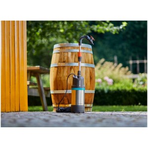 Pompe pour récupérateur d'eau de pluie Gardena 4700/2 inox automatic devant un tonneau en bois. Pompe électrique pour l'arrosage du jardin.