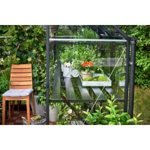 Tavolo a lamelle Halls nero nella serra Qube 68 con piante e accessori da giardino.