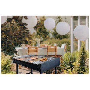 Barbecue à charbon noir Nouvel Mastergrill Ruote avec des aliments dans un jardin.