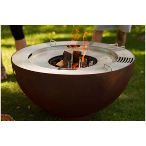 Brasero et barbecue Fireball Pro rouillé (Ø 100 cm) avec feu et surfaces de cuisson dans un jardin.