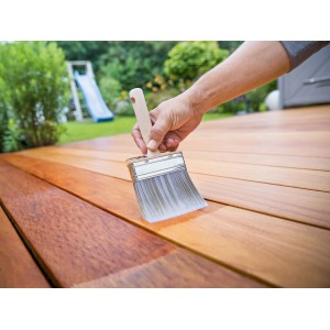 Mano che impregna una terrazza in legno con pennello piatto LUX 120mm. Pennello con serbatoio per impregnanti.