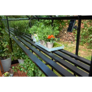 Tavolo a lamelle nero Halls Qube 68 in serra con piante.