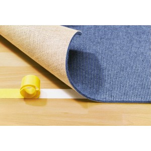 Ruban adhésif double face LUX fixant la moquette sur un plancher en bois. Rouleau visible.