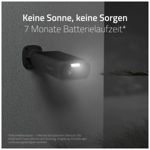 Caméra de surveillance solaire Hombli noire avec projecteur allumé sur mur gris la nuit.
