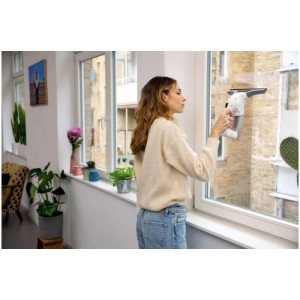 Femme nettoyant une fenêtre avec le nettoyeur de vitres sans fil Kärcher WV 1 Plus. L'aspirateur de fenêtre assure une propreté sans traces.