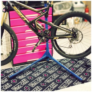 Fahrrad auf Montageständer auf Muc-Off Werkstattmatte. Ideal für Fahrradpflege und Reparatur.