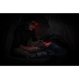 Homme lisant dans une tente avec une lampe frontale rouge Energizer. Lampe frontale universelle avec 2 piles AAA incluses.