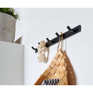 Schwarze Hettich Garderobenleiste aus Metall mit 5 matten Haken an weißer Wand, mit Korb und Scrunchie.