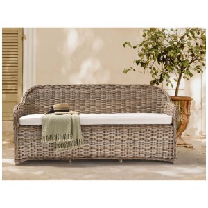 Banc de jardin Susua en rotin tressé couleur naturelle avec coussin blanc sur une terrasse.