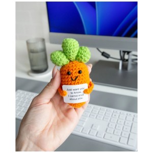 Hand hält gehäkelten Glücksbringer Karotte mit lächelndem Gesicht und Spruch "I carrot a lot about you".