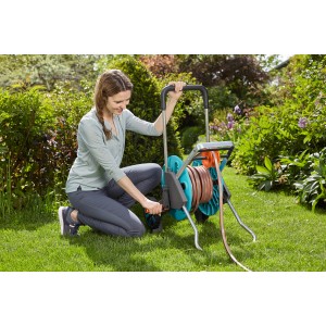 Donna utilizza l'avvolgitubo Gardena AquaRoll M Easy Set in giardino.