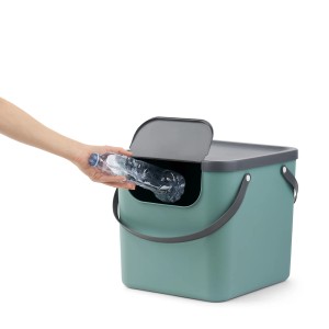 Cestino riciclaggio Rotho Albula (40 l, Mistletoe Green) con mano che getta una bottiglia di plastica.