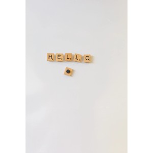 Aimants Fix-o-moll : « HELLO » épelé avec des lettres en bois sur un mur blanc.