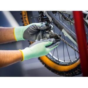 Mani che puliscono la catena della bici con i guanti LUX Tank (taglia 10). Guanti da lavoro rivestiti in nitrile.
