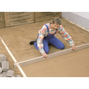 Un homme nivelle une chape avec la règle à dresser LUX Classic 2 m. Outil de maçonnerie en utilisation.
