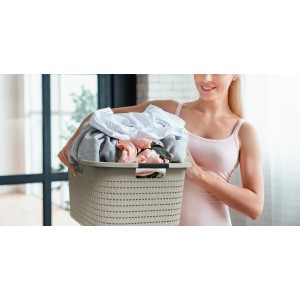 Donna che trasporta cesto portabiancheria Rotho Country 40 l Cappuccino effetto rattan, pieno di bucato.