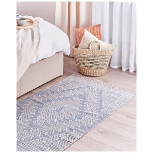 Tapis en coton bleu Ansar (80x150 cm) avec motif géométrique dans une chambre.