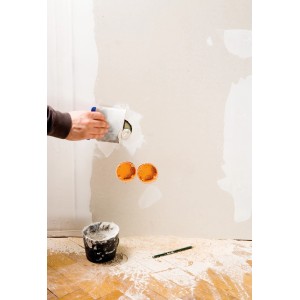 Artisan appliquant du mastic sur un mur avec un jeu de spatules japonaises LUX. Outil et mastic utilisés.